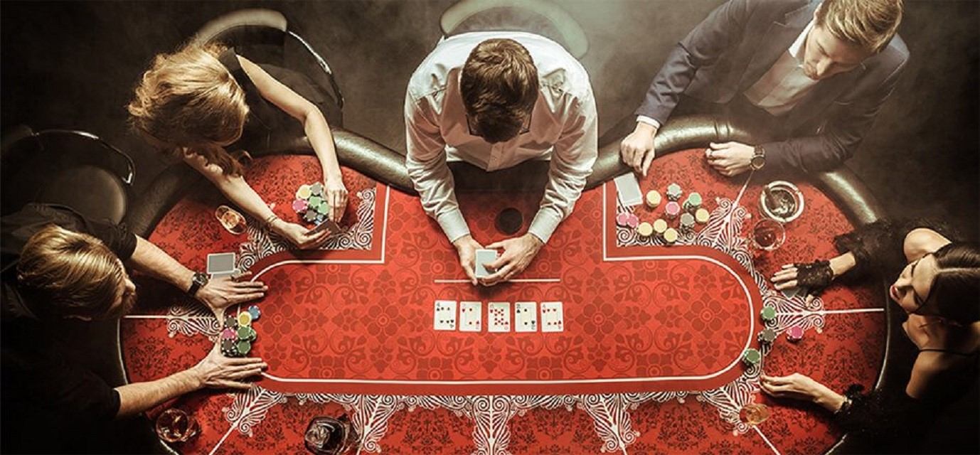 Overhead view of poker table with players holding cards and stacks of chips.