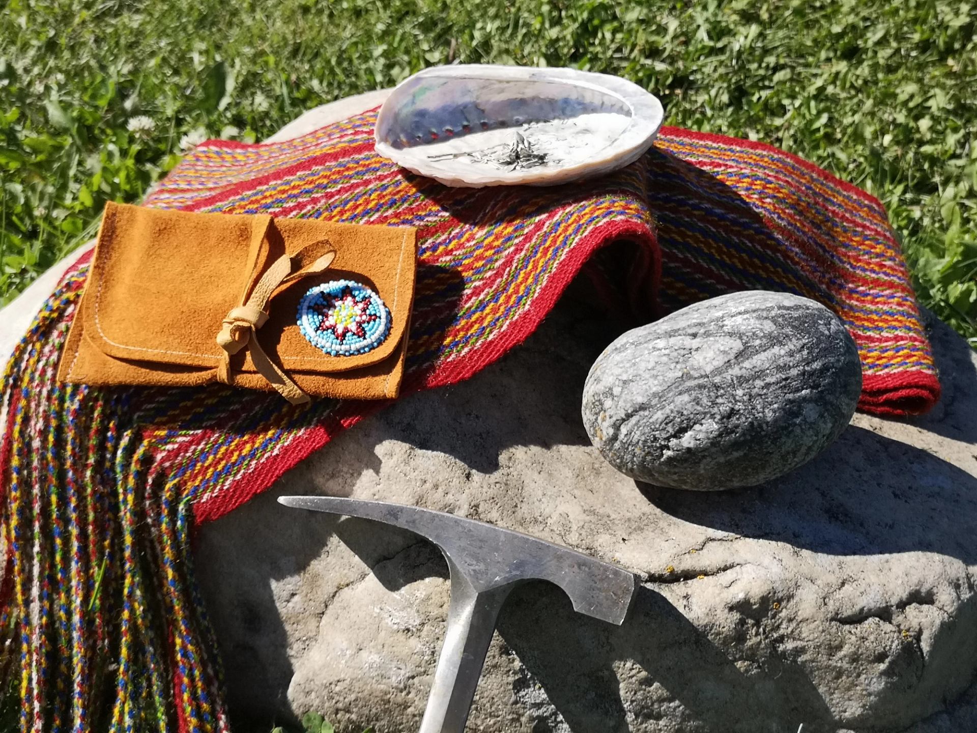 Geology hammer, rock specimen, First Nations and Métis cultural items displayed on a grave site.