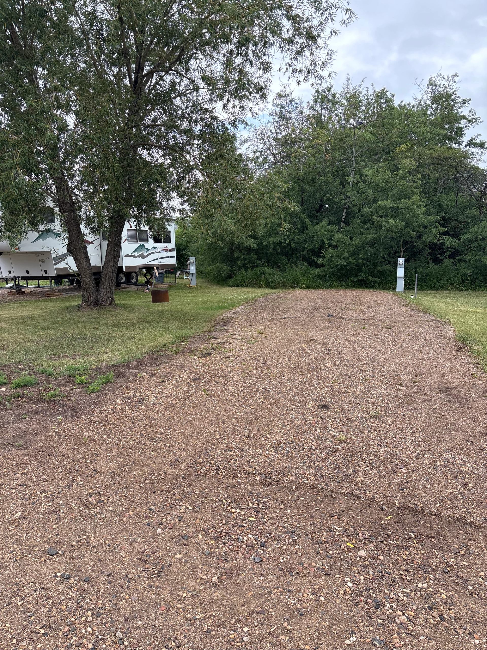 Gravel RV site surrounded by trees at Lamont RV Park and Campground.