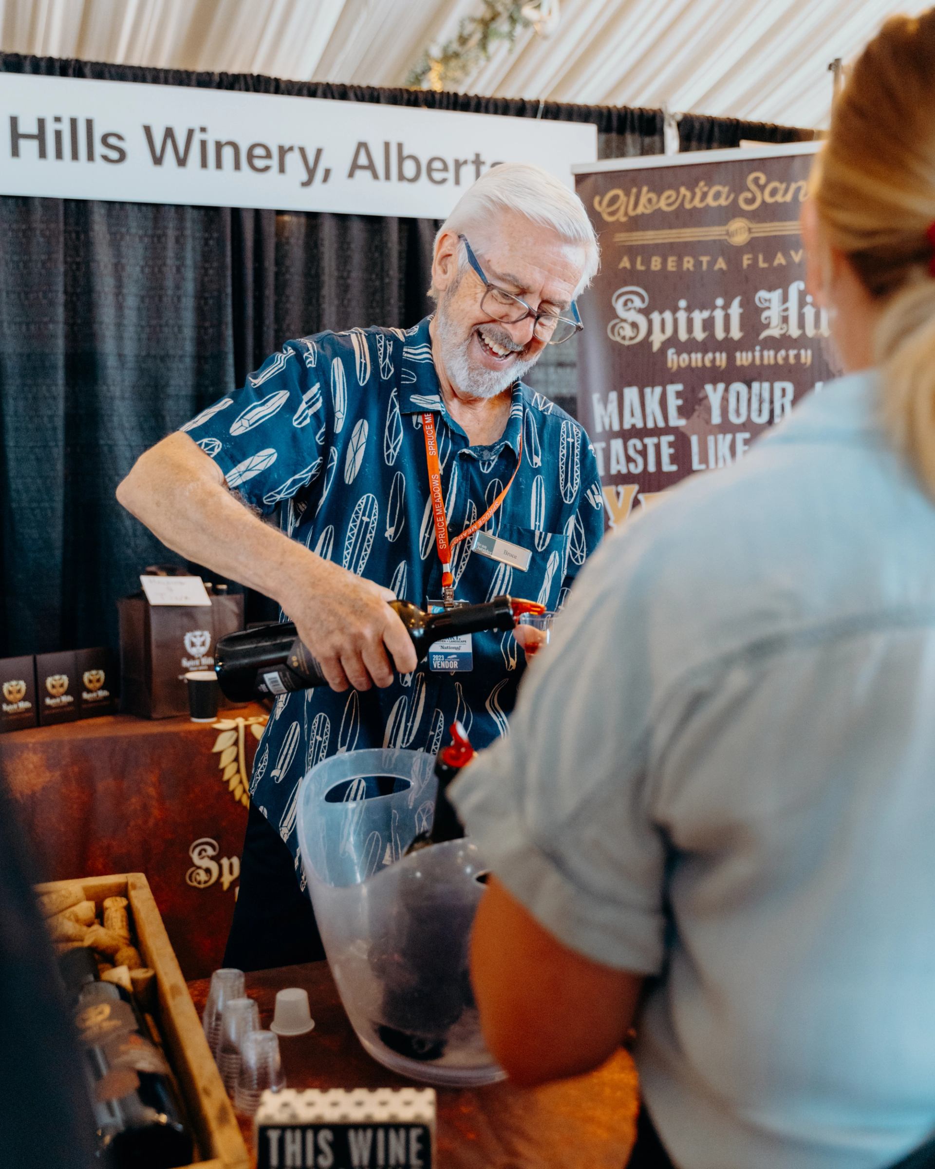 A vendor pours samples for guests at an Alberta winery display booth.
