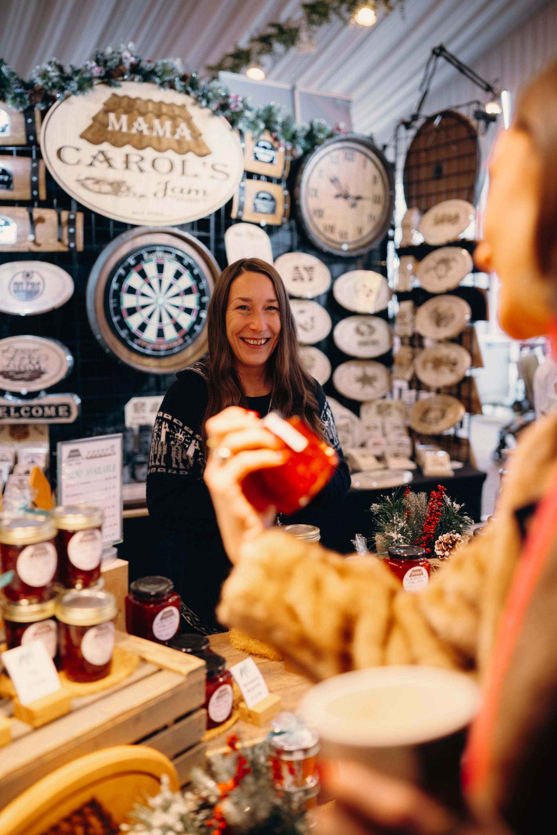 Customer browsing a booth of handmade goods at the International Christmas Market.