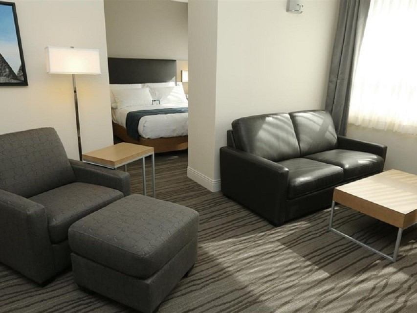 Suite with leather seating, armchair, and bed in separate area at Best Western Plus.