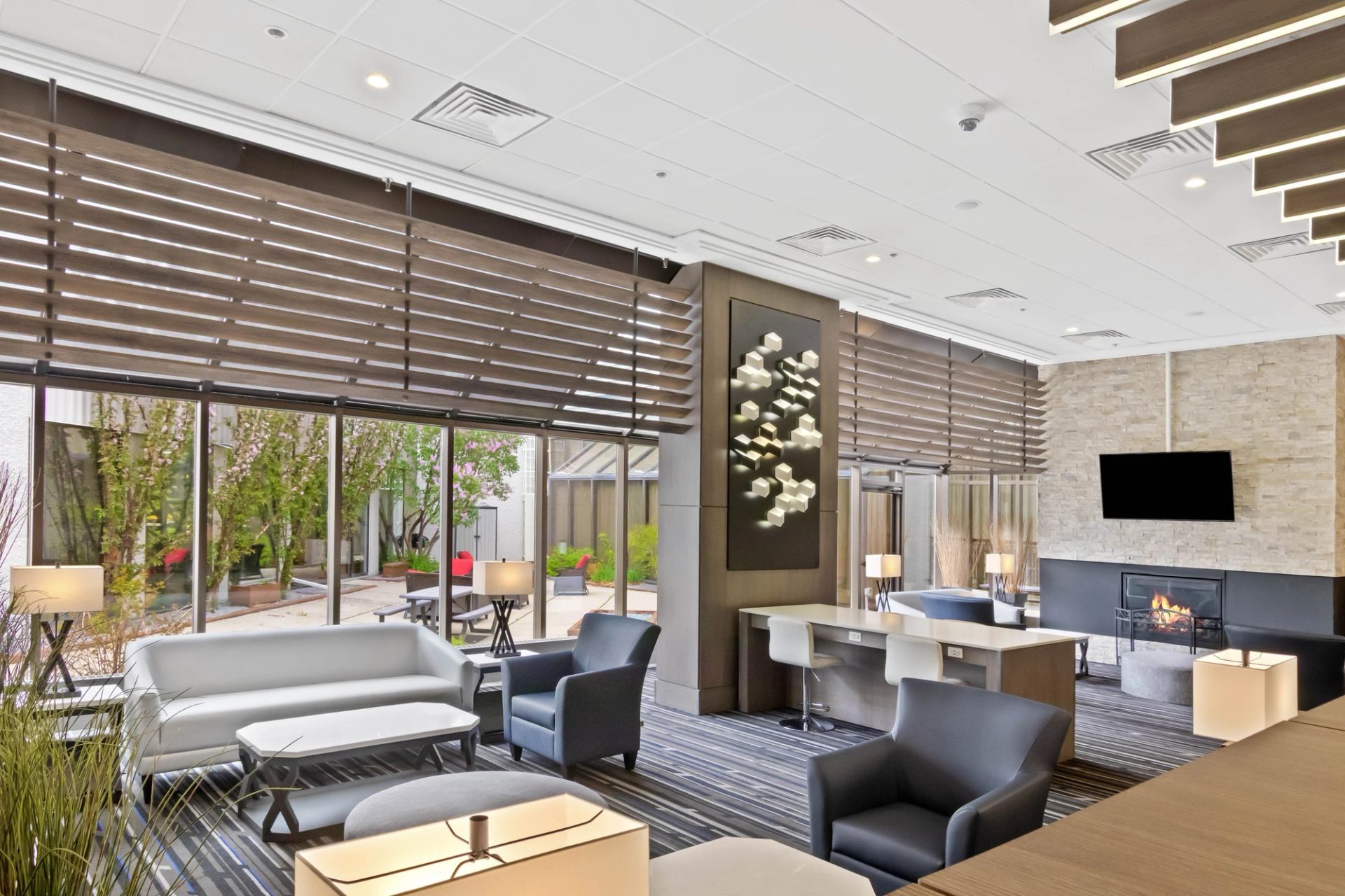 Modern lounge with sofas, courtyard view, wall art, fireplace and television.