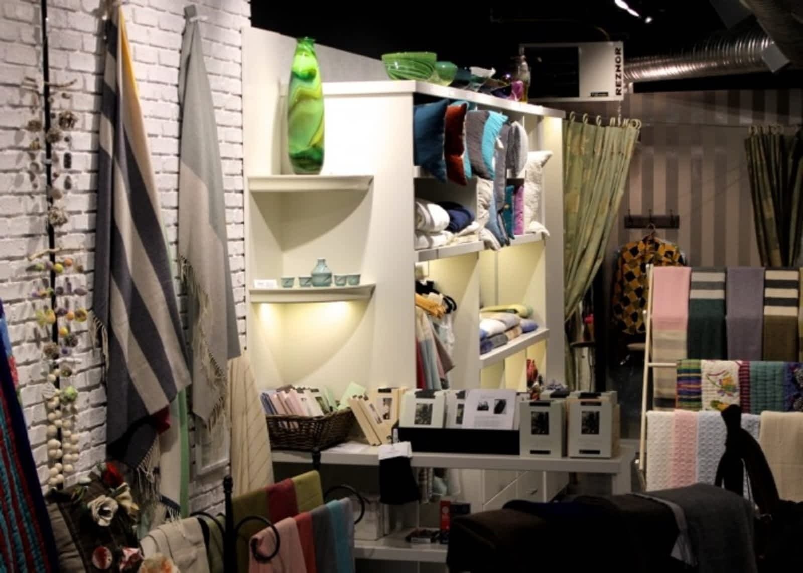 Home decor store with folded textiles, soft lighting, and hanging fabric display.