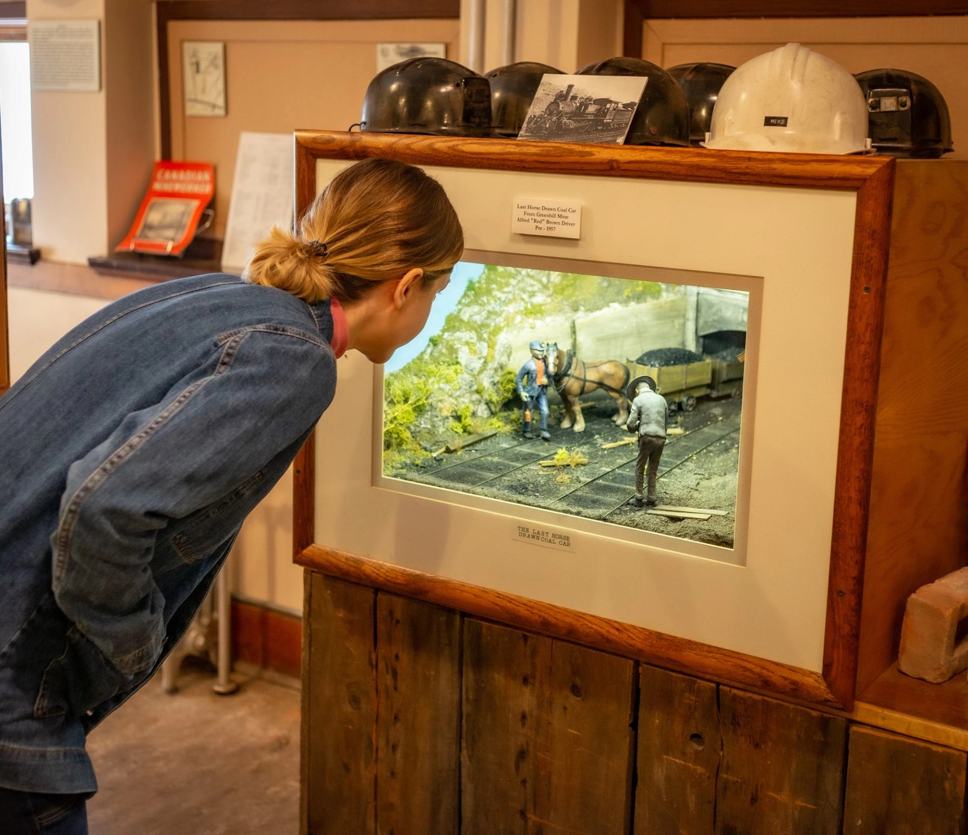 Museum exhibit display with visitor viewing model of horse-drawn coal car diorama.