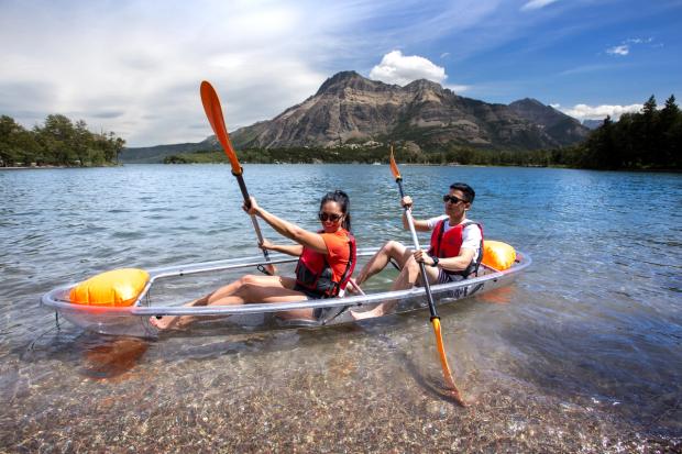 Couple canoeing in a clear bottom canoe on Waterton Lake.