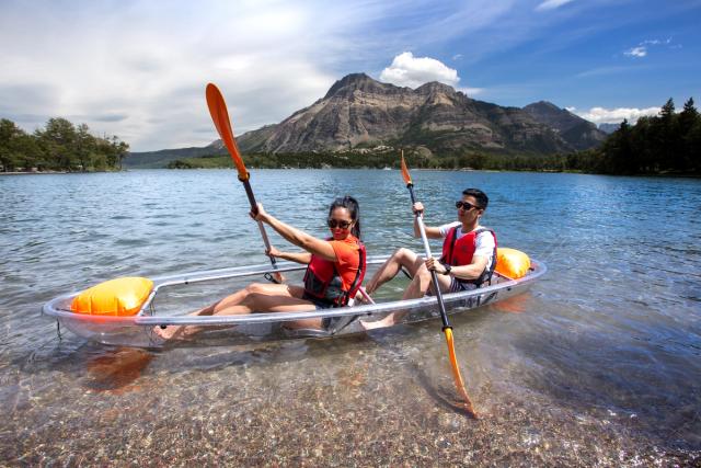 Couple canoeing in a clear bottom canoe on Waterton Lake.