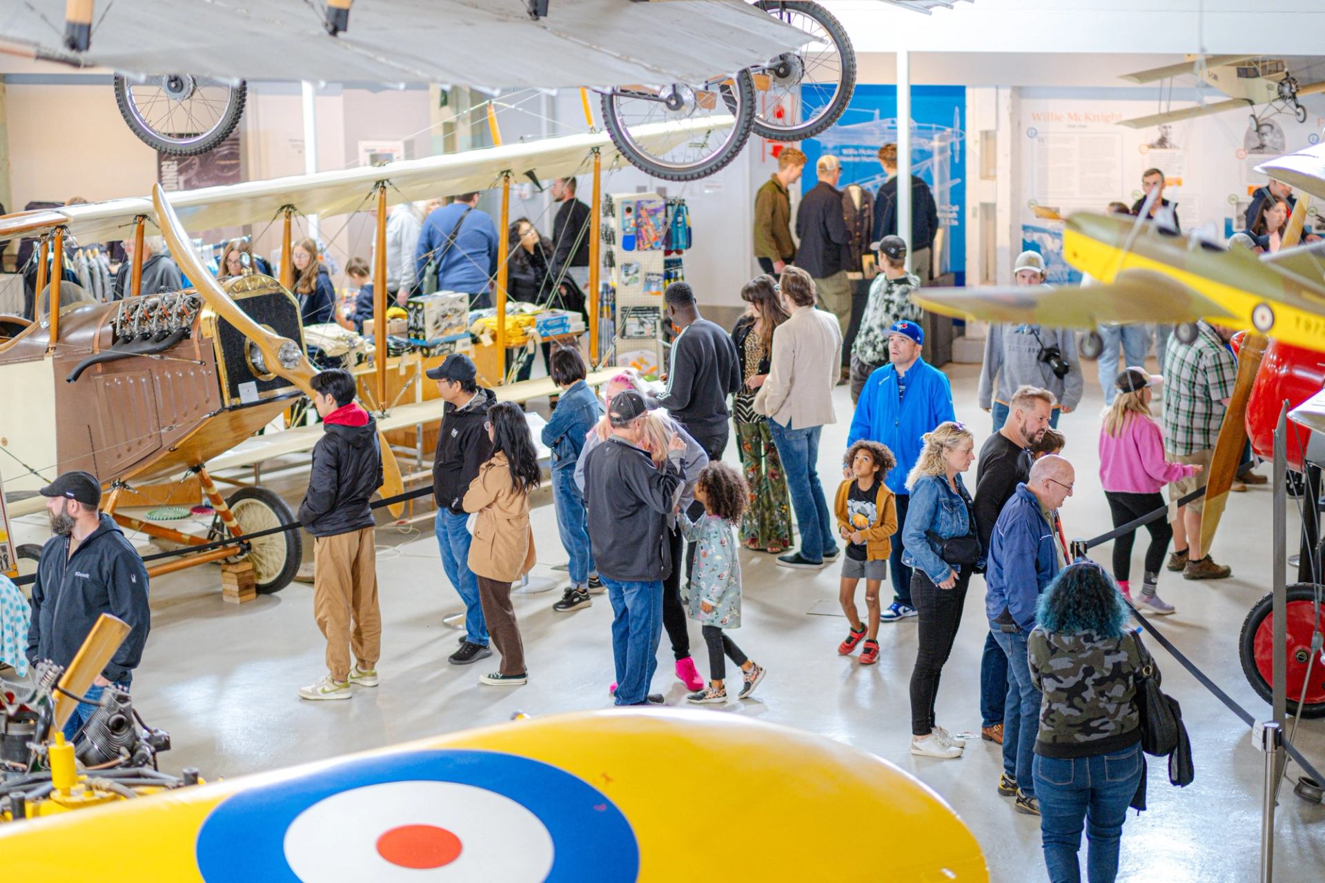 Crowds walking among historic aircraft displays at The Hangar Flight Museum on Family Day.