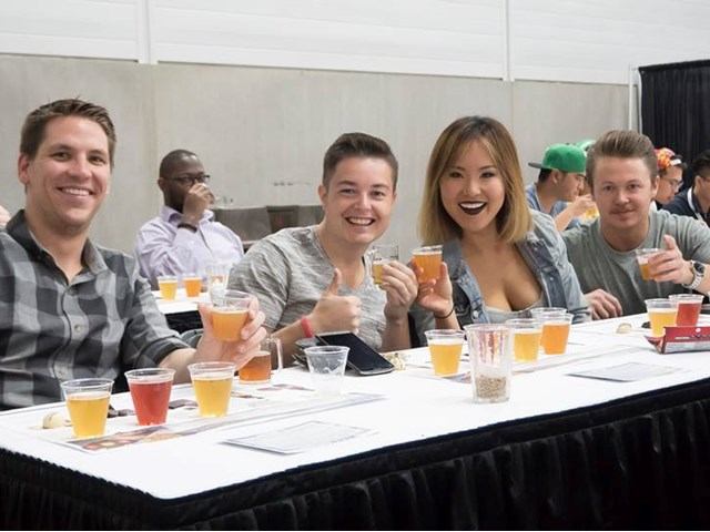 Group tasting various beers at a table during indoor beer festival.