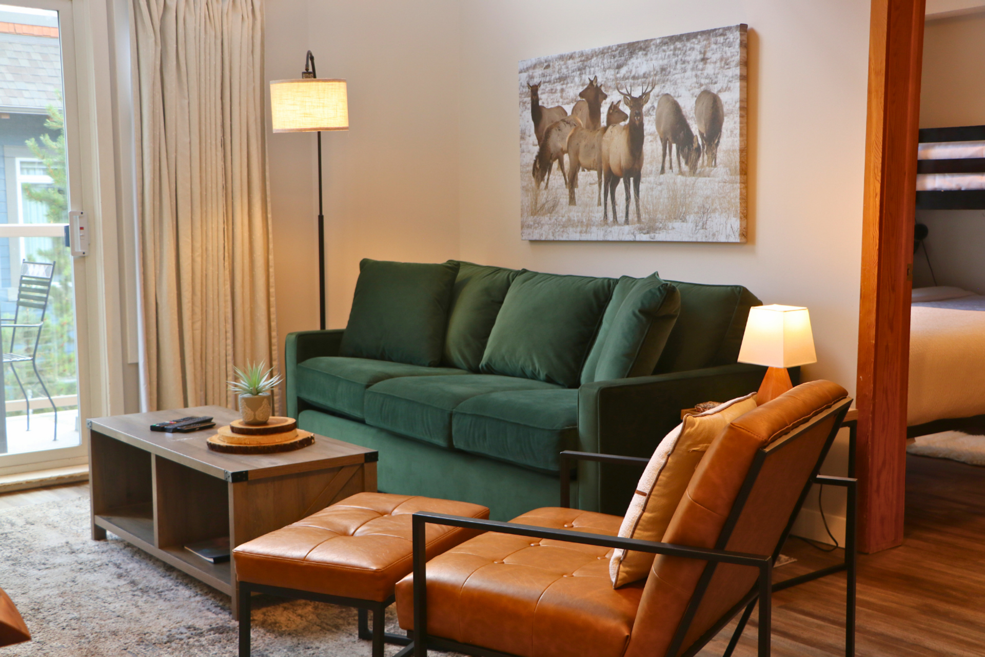 Living room with green sofa, leather chair, coffee table and elk artwork.