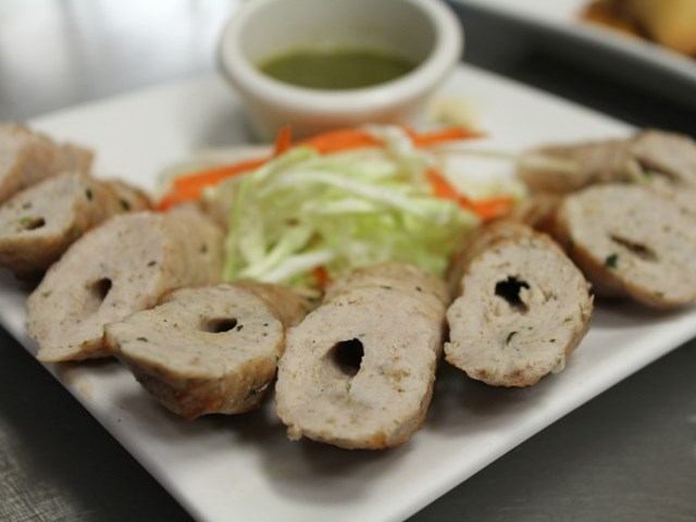 Sliced sausage dish with shredded veggies and green sauce at Tandoor n Flame.