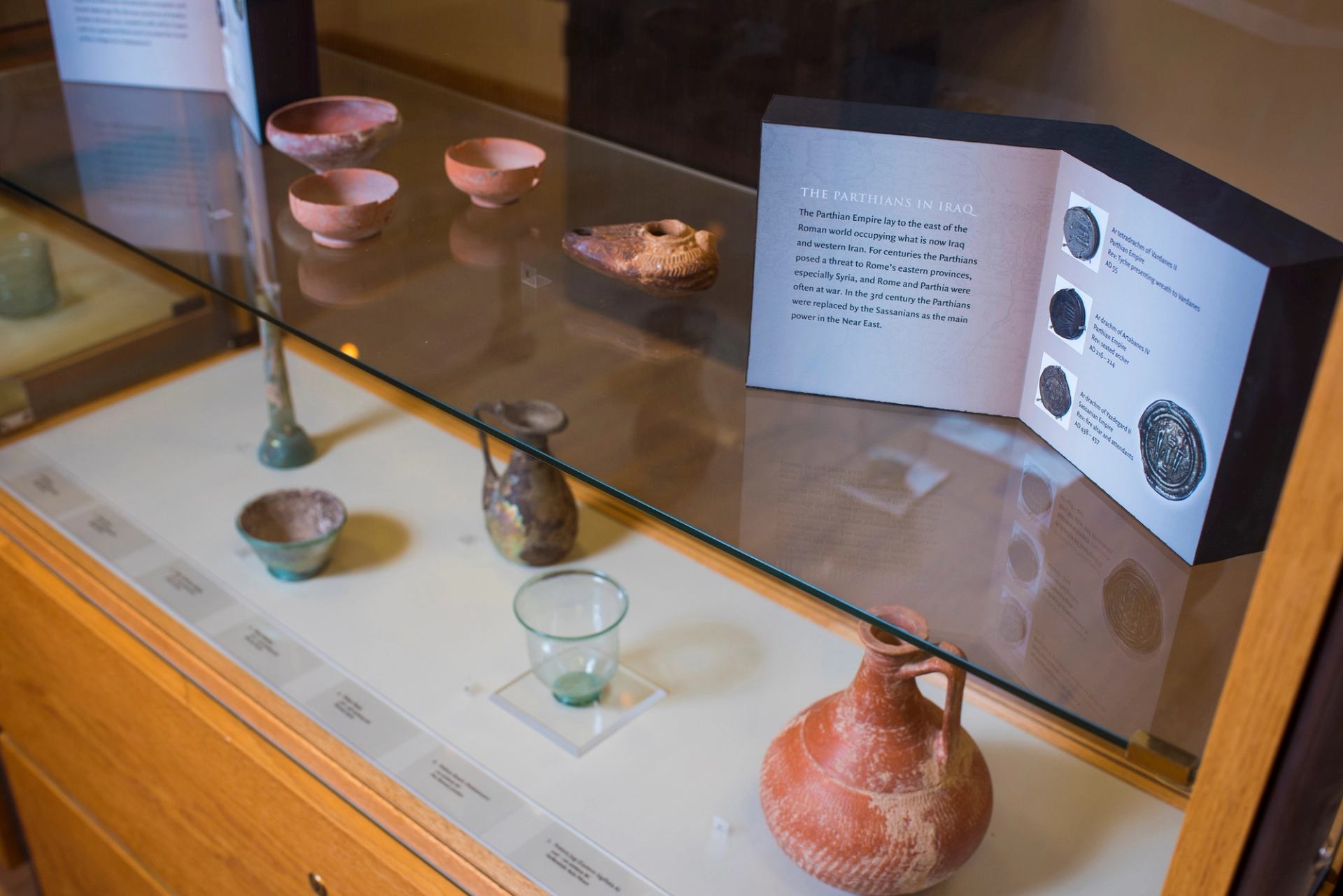 Glass and ceramic vessels arranged in a museum case with an informational booklet.