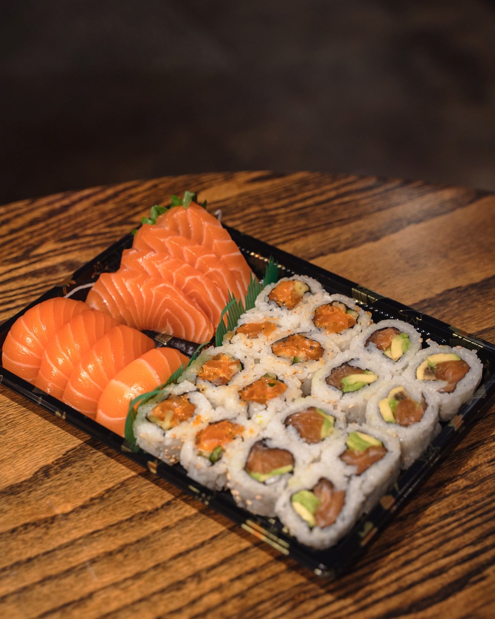 Sushi platter with salmon nigiri and sliced rolls on a wooden table.
