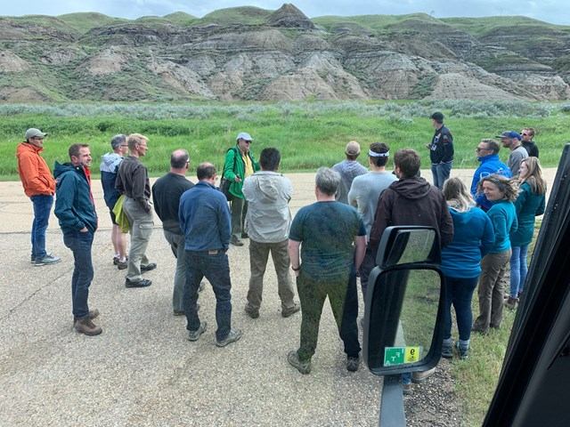 Group gathered on roadside with green hills and rock formations
