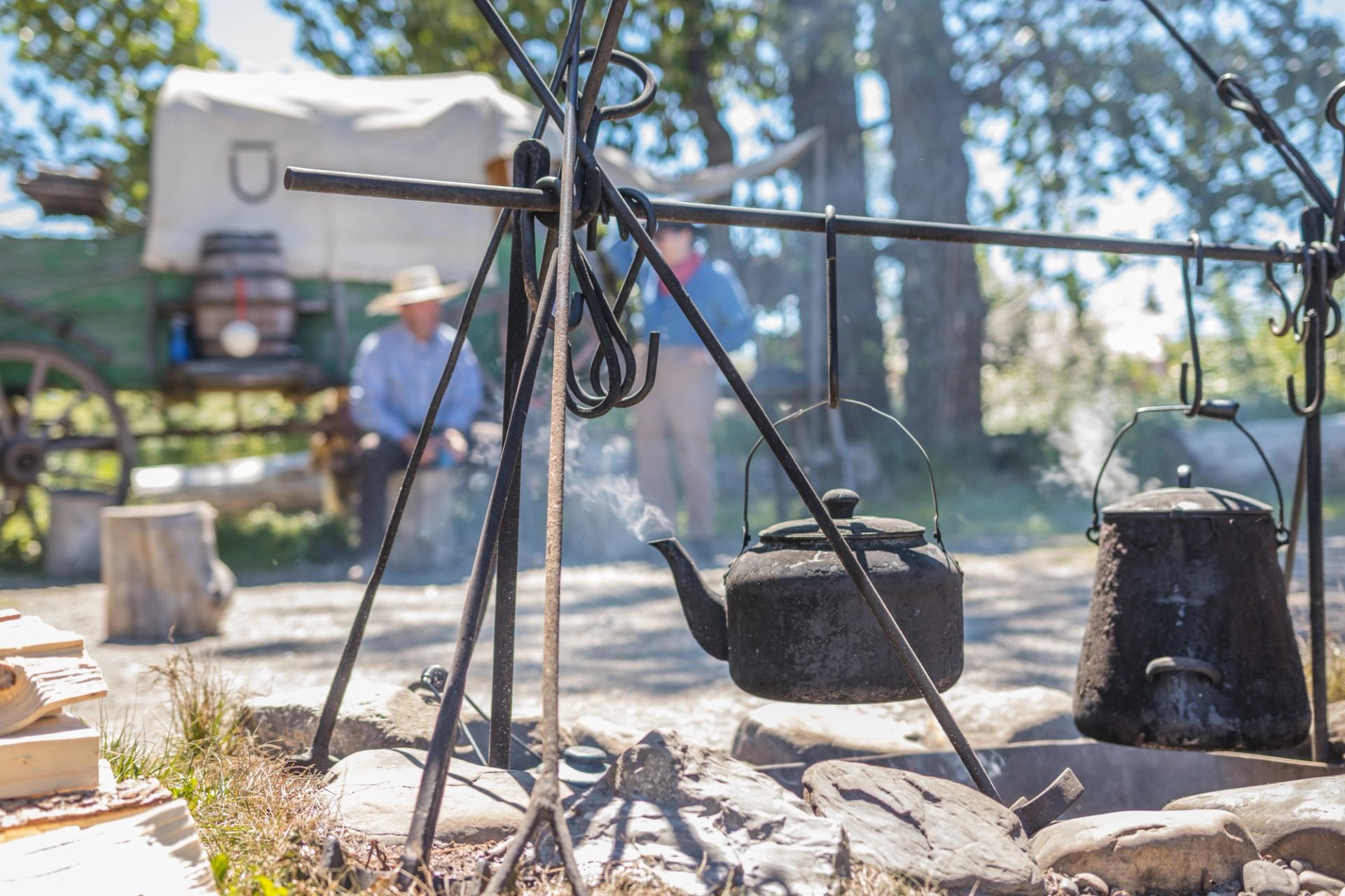 Cast iron kettles hang over an outdoor fire pit at a historic ranch site.