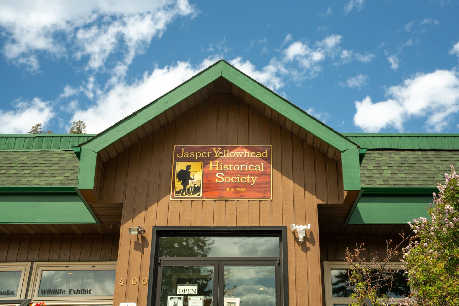Entrance of Jasper Yellowhead Museum with sign under a gabled roof and blue sky.