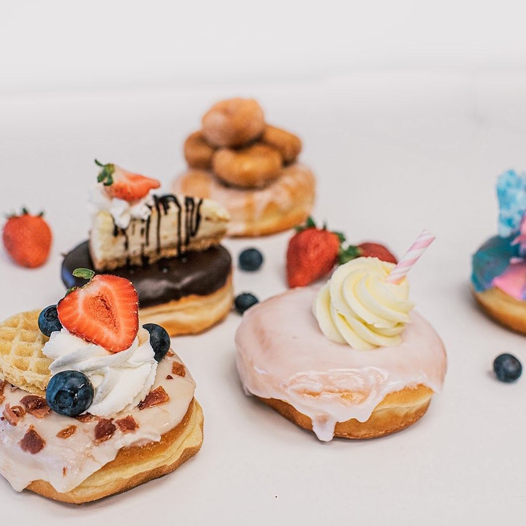 Assorted donuts with fruit, cream, and colorful toppings on white background