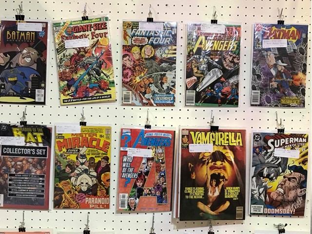 Comic books in plastic sleeves clipped to a pegboard display wall.