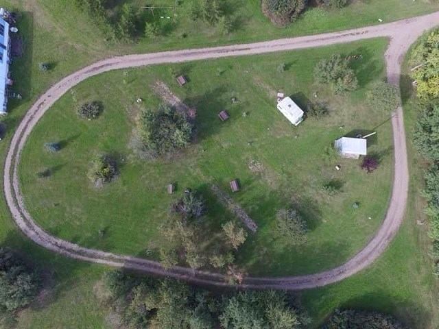 Aerial view of a grassy oval loop with scattered trees, campsites, and two small structures.