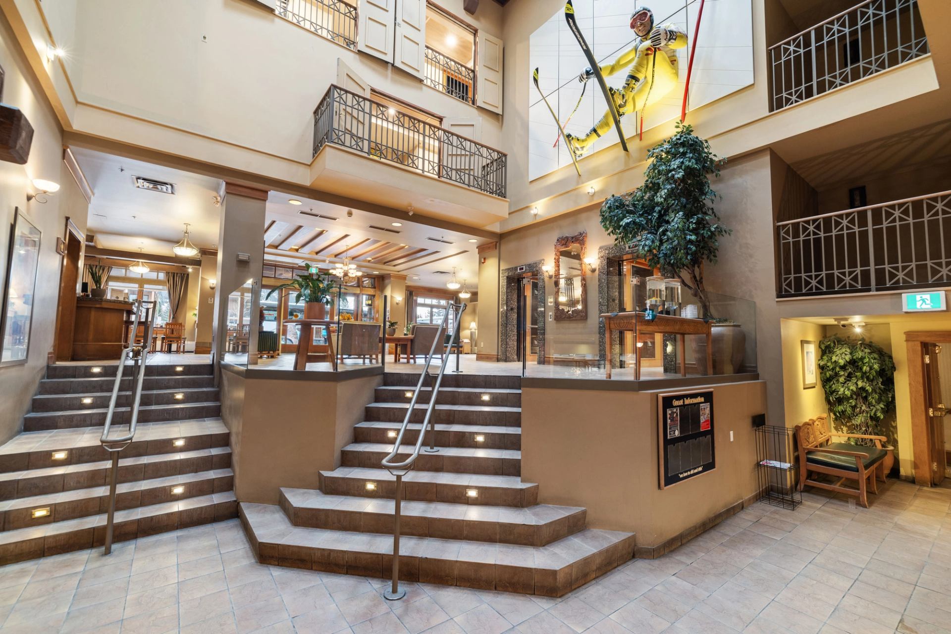 Atrium with wood accents, balconies, a large skier statue, and seating at Banff Ptarmigan Inn.