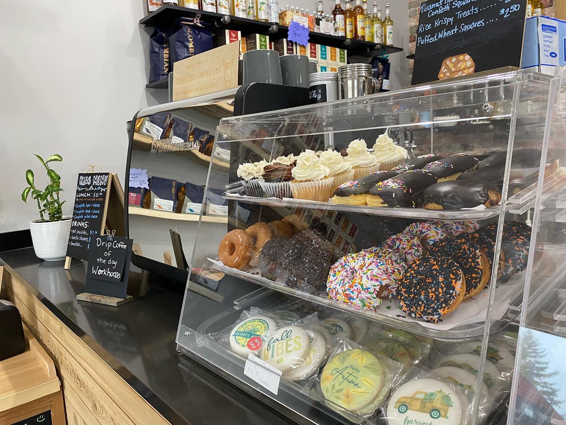  Display case with pastries, menu signs, and shelves of goods inside Farmstead Market & More Bistro.