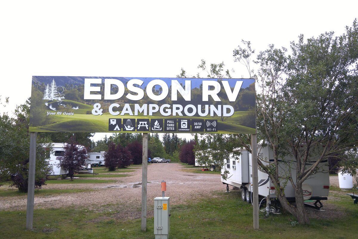 Large Edson RV and Campground sign above a gravel road with RVs and trees behind.