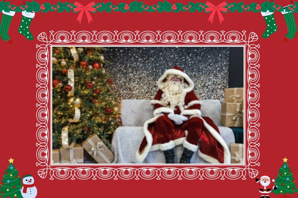 Santa Claus seated on a couch beside a decorated Christmas tree and wrapped gifts.