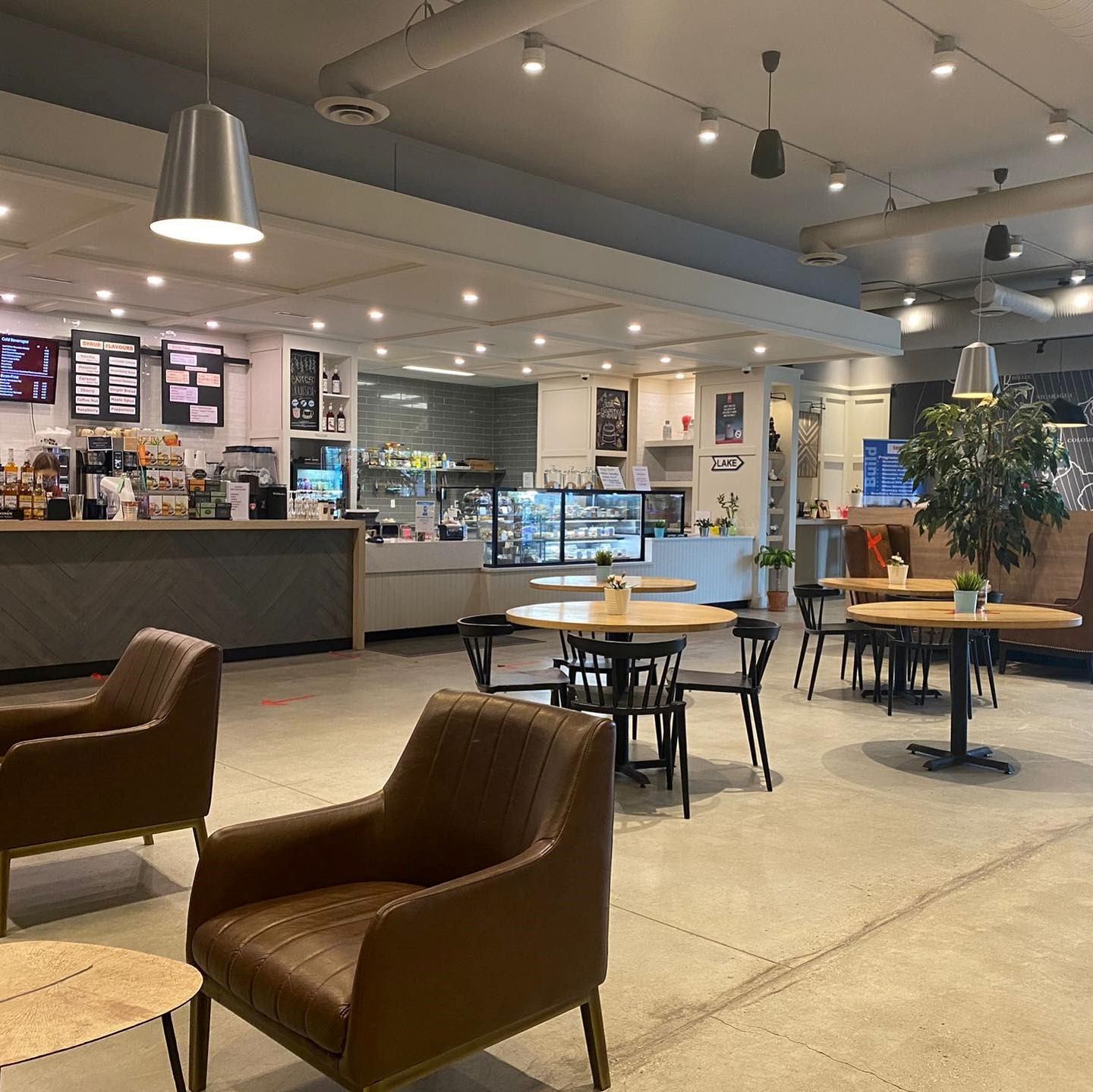 Spacious cafe with leather chairs, round tables, and a bright, modern interior.