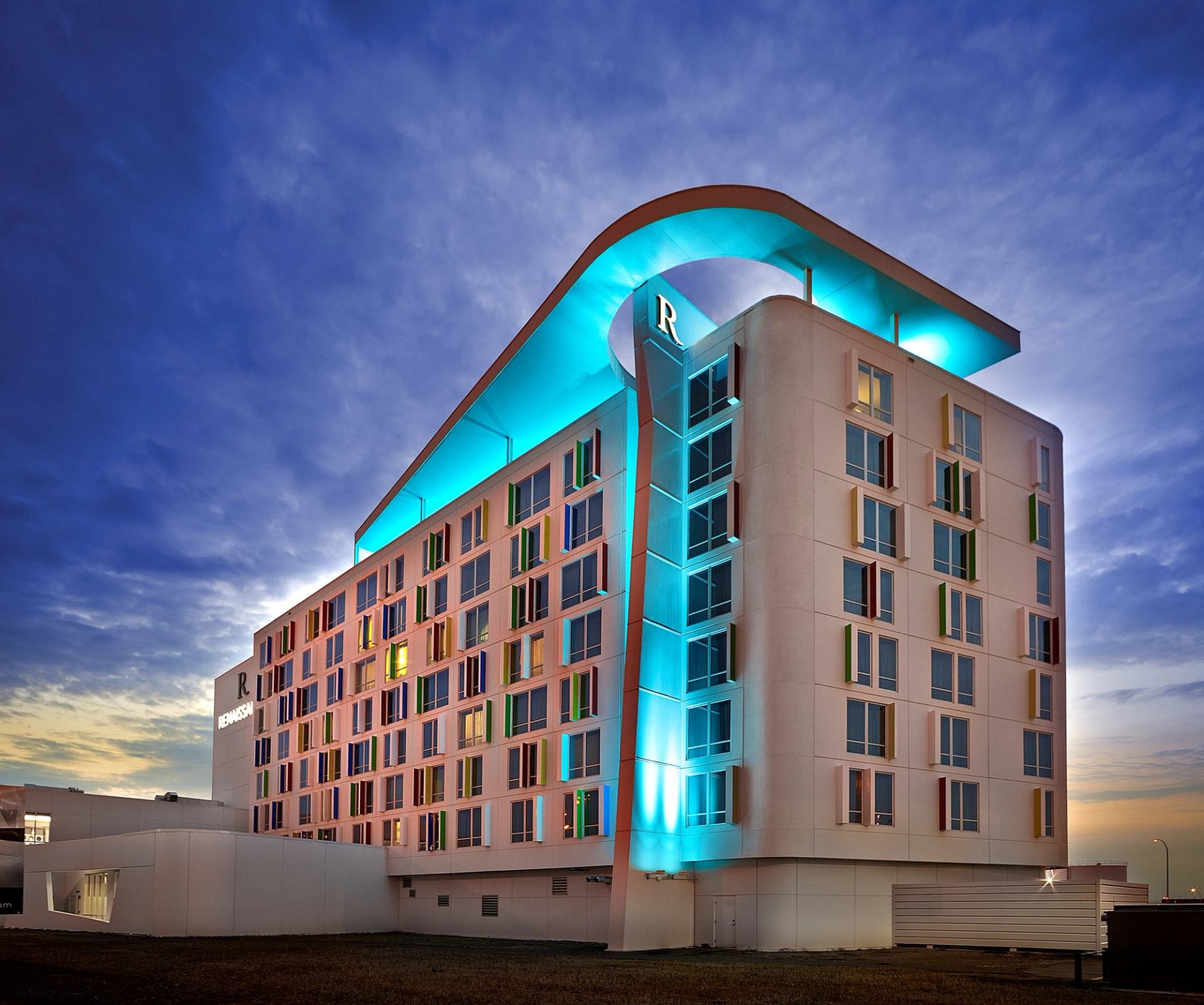 Modern hotel with curved roof and blue lighting at Edmonton Airport.