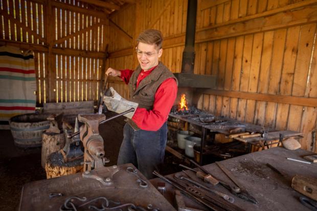 Man doing a blacksmith demonstration at Rocky Mountain House.