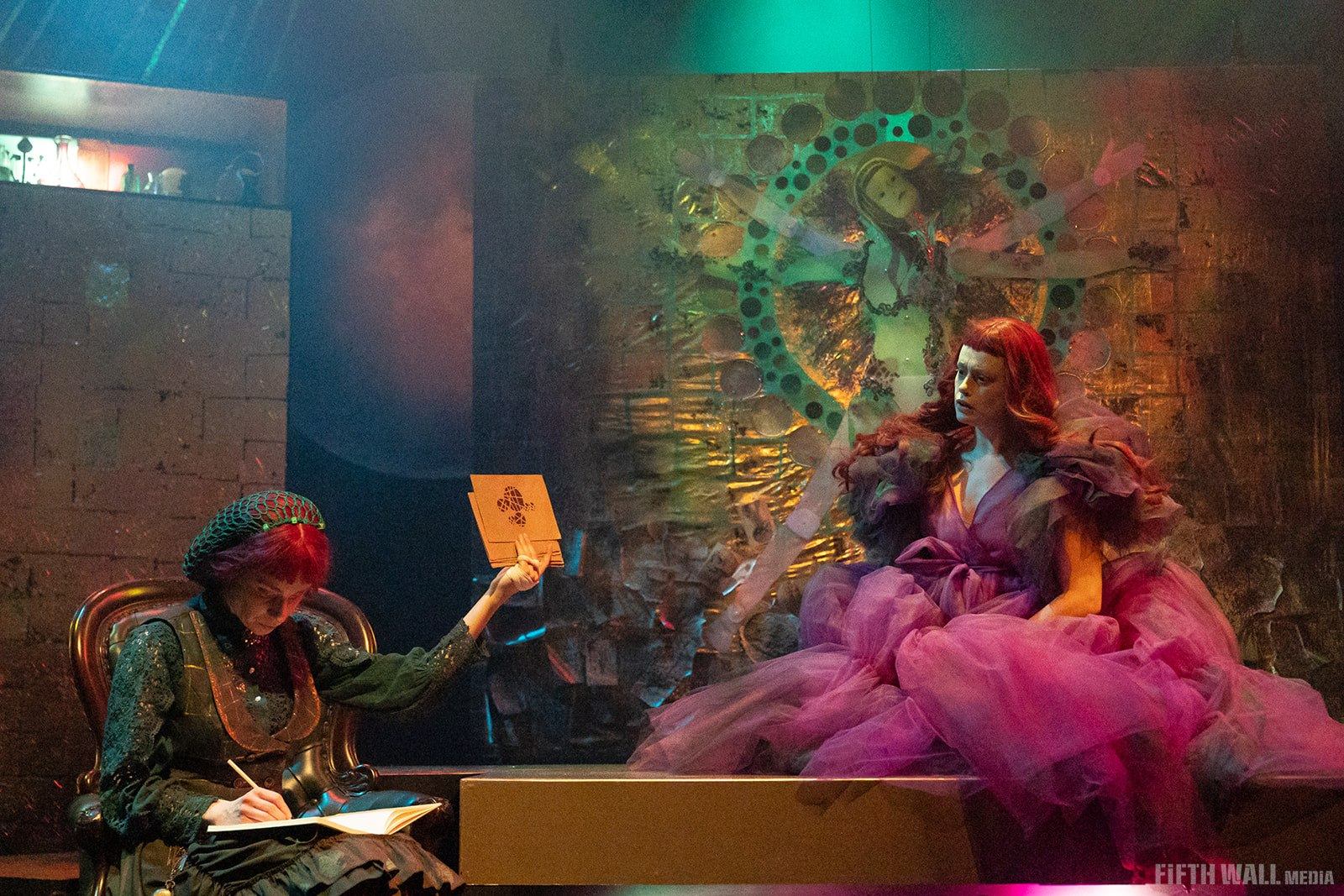 Theatre scene with two performers, one sketching, one in voluminous pink gown.