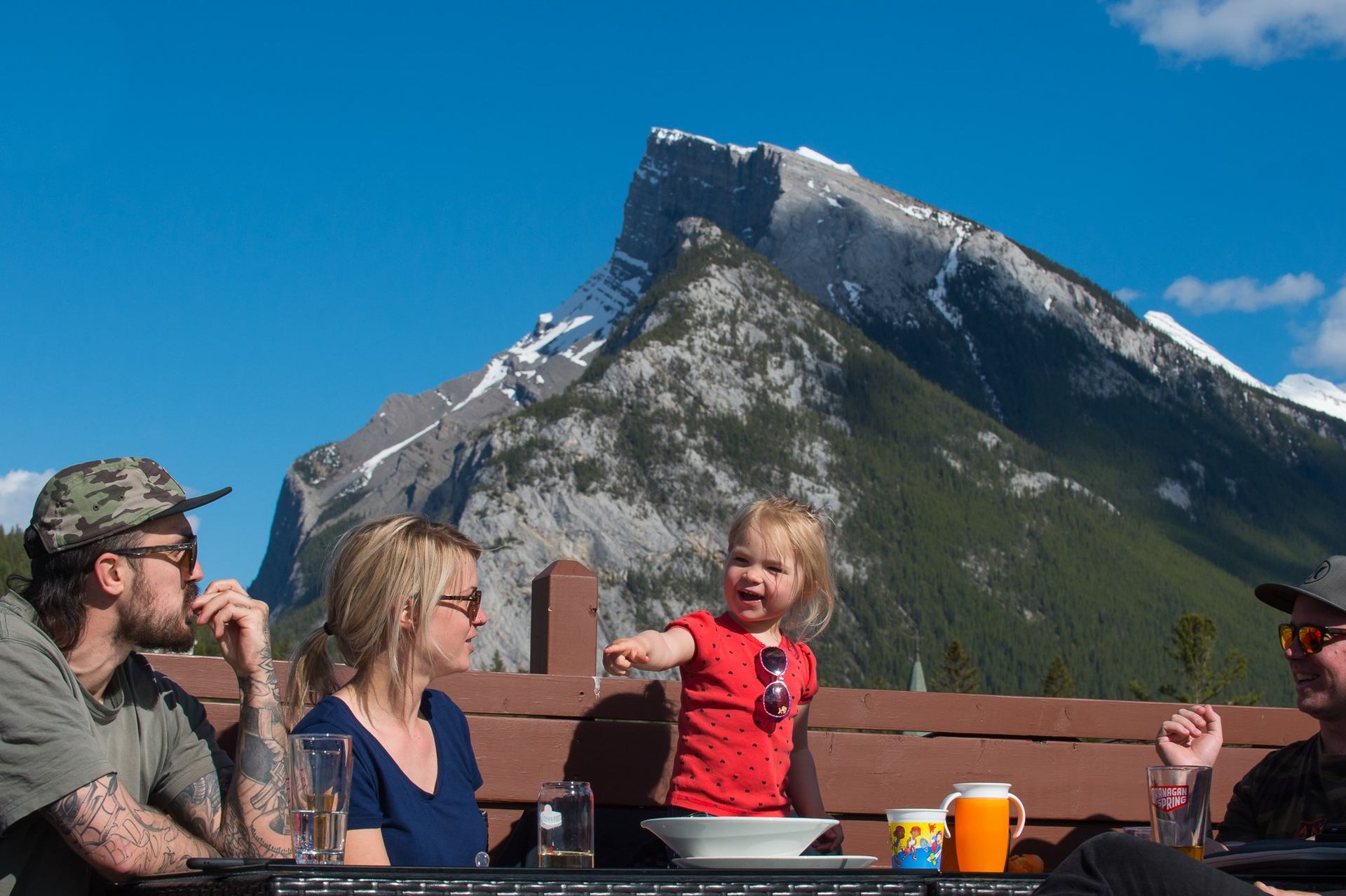Group dining outdoors at Elk & Oarsman with a stunning mountain backdrop.