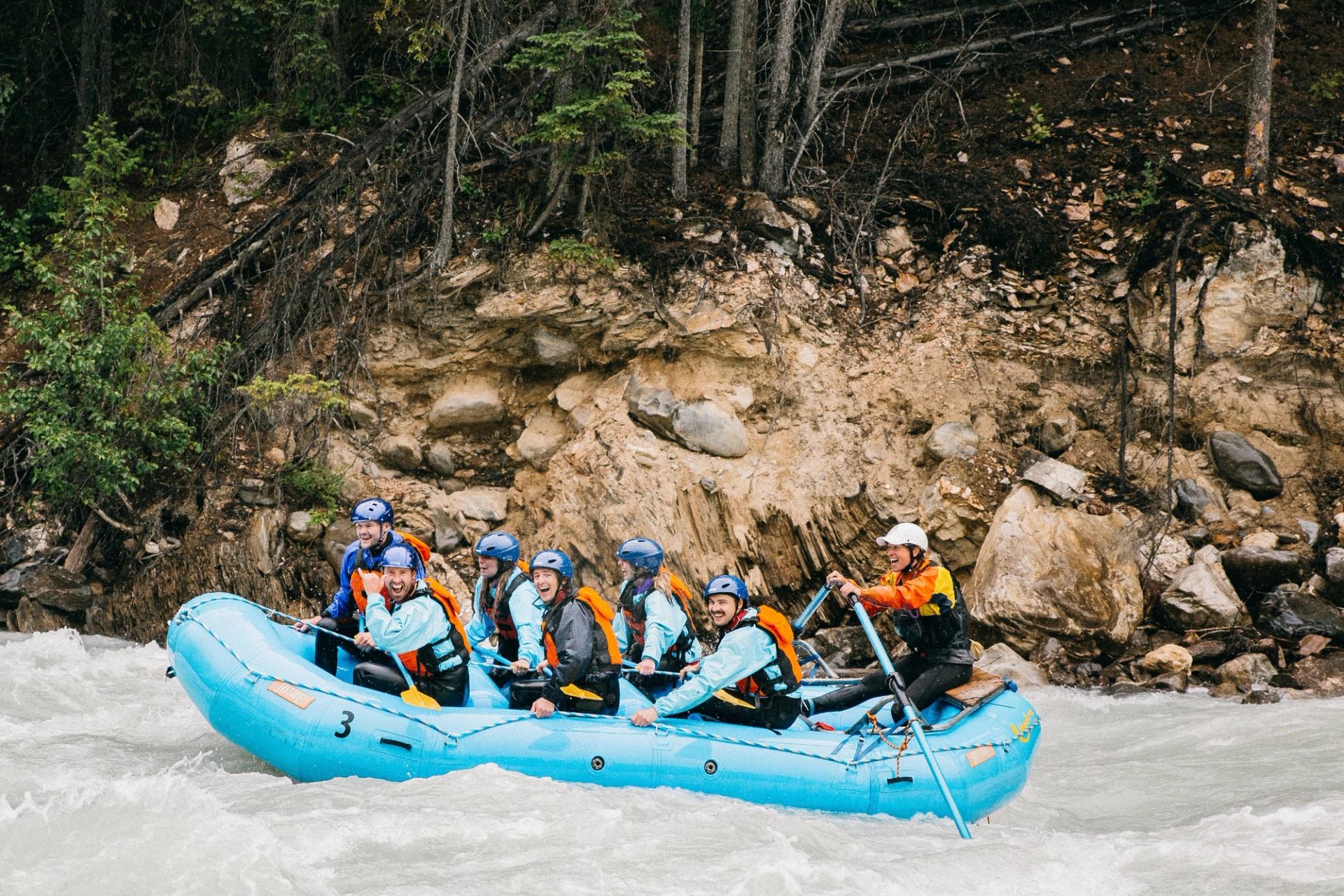 Group rafting through fast whitewater beside rocky canyon walls in Banff.