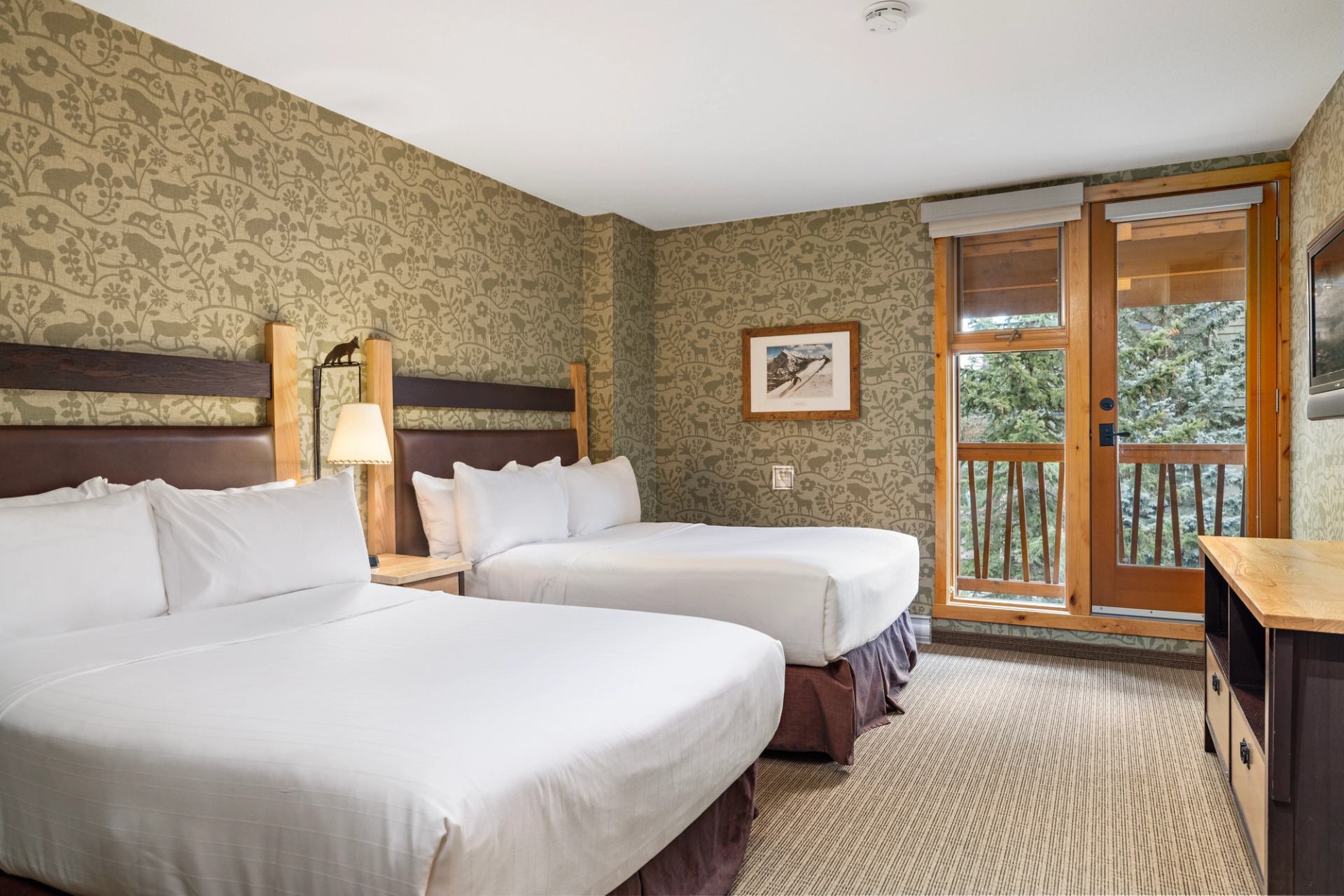 Double-bed room at Fox Hotel with warm lighting and cozy decor and trees out the window.