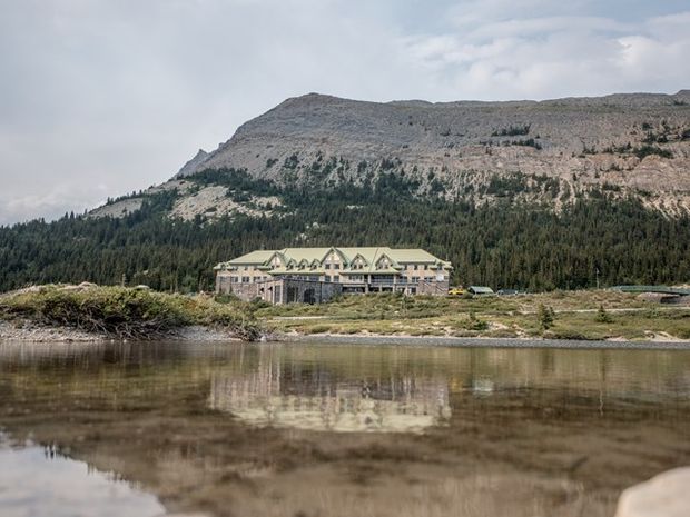 View of the Columbia Icefield Discovery Centre building reflecting in a lake along the Icefields Parkway.