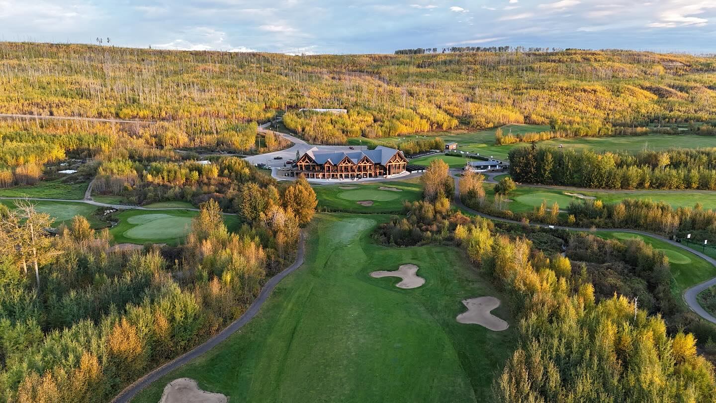 An aerial view of the golf course surrounded by rolling hills and dense autumn trees.
