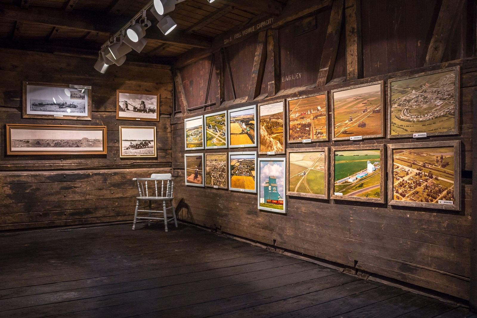 Rustic gallery with framed aerial and historical photos on wooden walls.