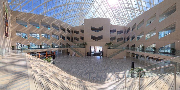 Visitors view the spacious City Hall atrium featuring glass ceilings, stairways, and open levels.