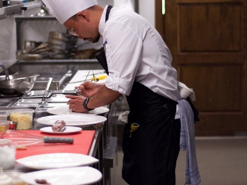 Chef preparing dish in professional kitchen.