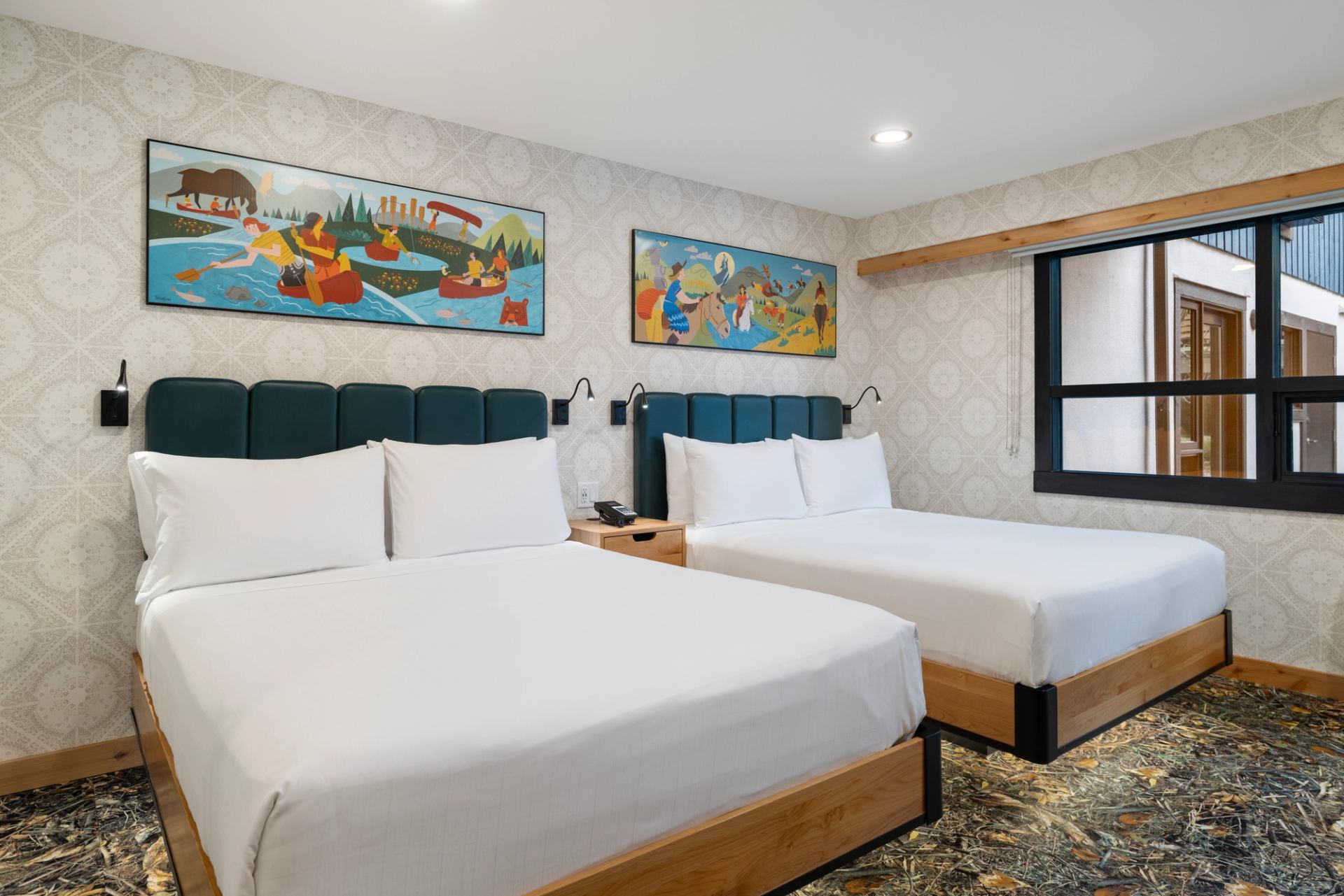 Double-bed room at The Dorothy Motel with teal headboards and vibrant artwork.