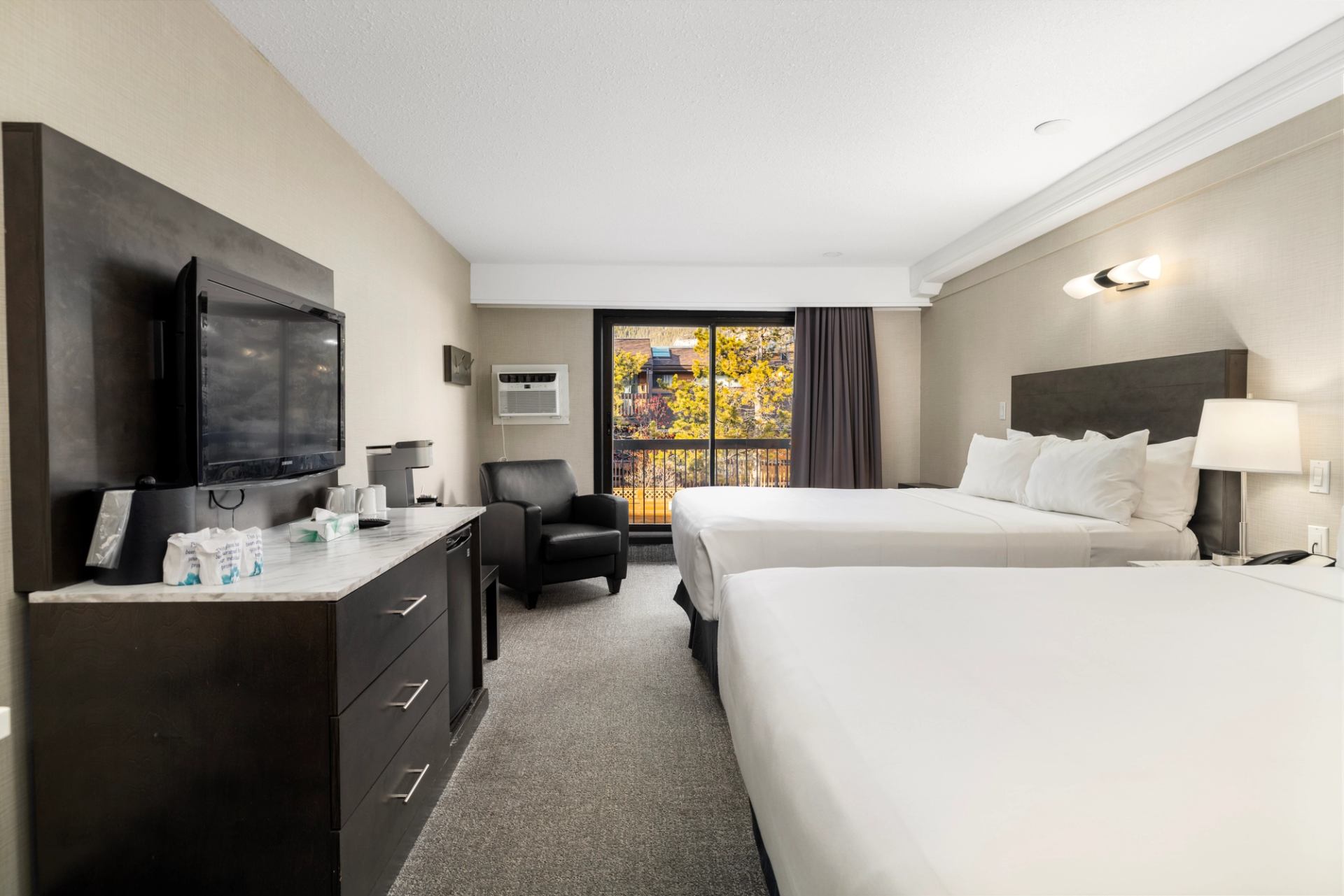 Hotel room with two double beds, flat-screen TV, and natural light.