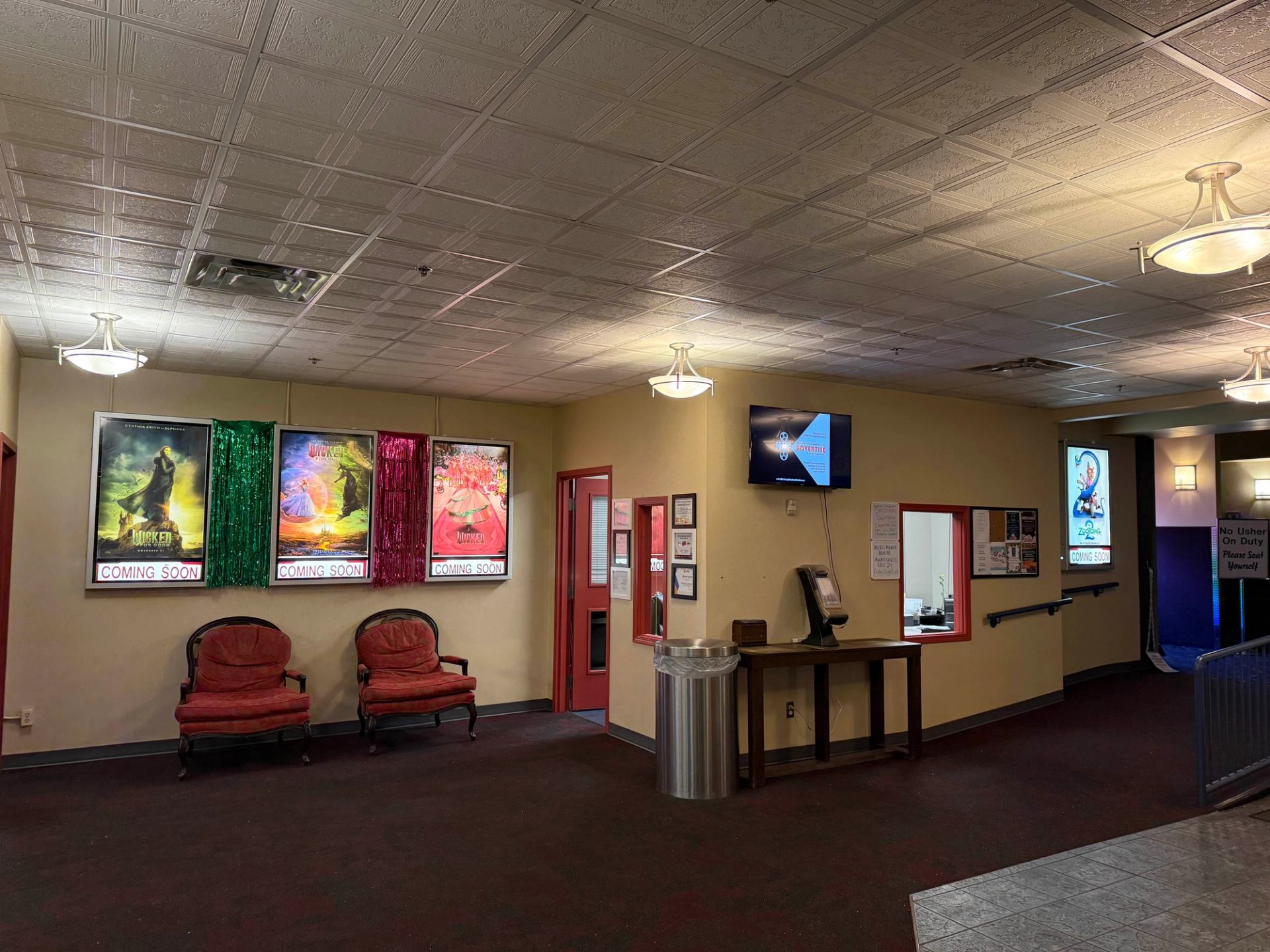 Cinema lobby with colorful movie posters, seating area, and ticket counter.