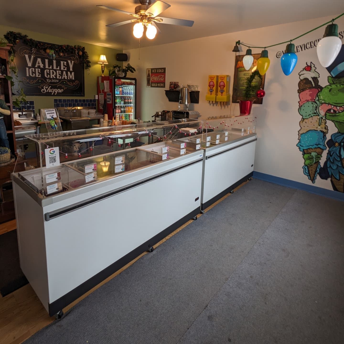 Interior of Valley Ice Cream Shoppe with ice cream display freezers, colorful mural, and menu boards.