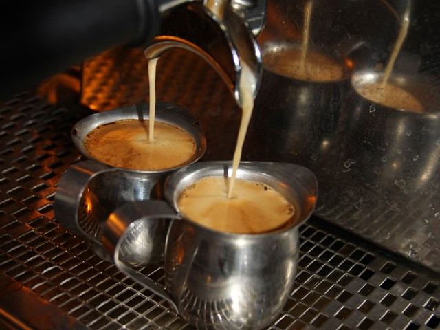Espresso pouring into metal pitchers from a coffee machine at Cafe Bicyclette.