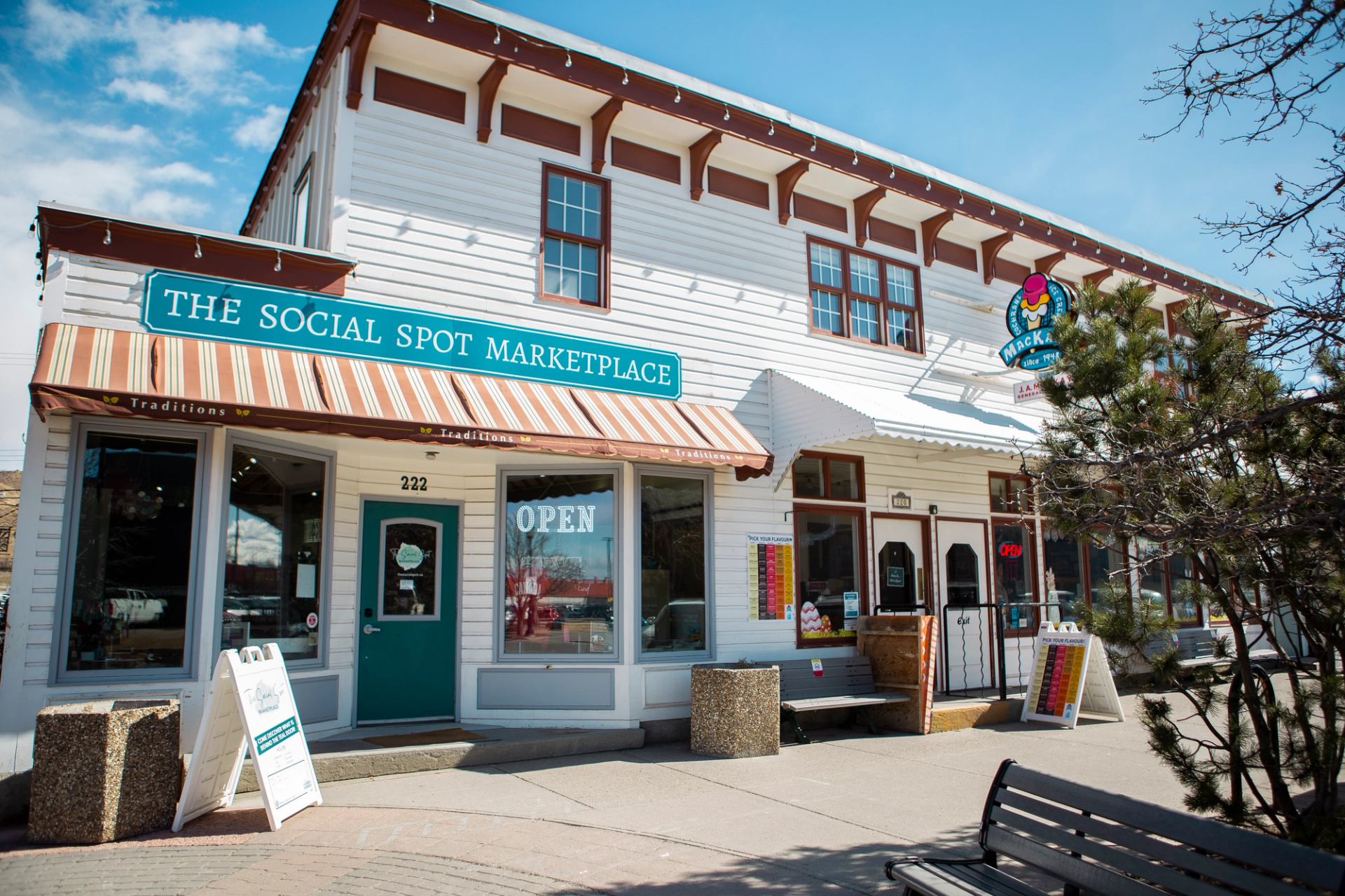 A historical cream and red building on a sunny street with a teal door and an open sign