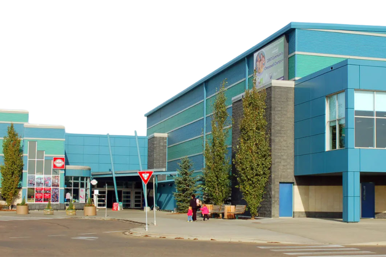 Modern blue building with glass panels and trees near the entrance.