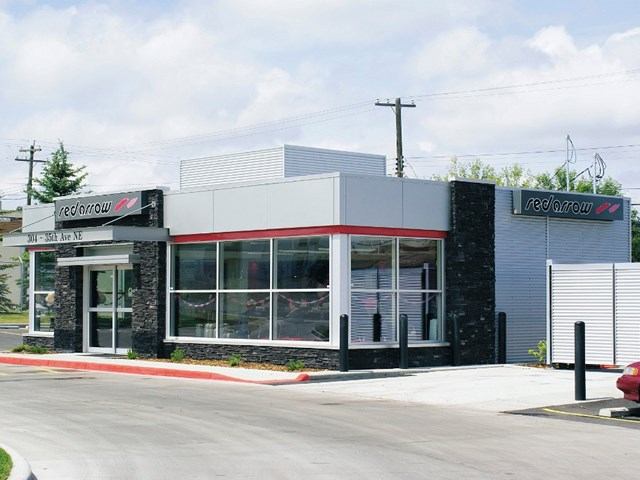 Red Arrow Motorcoach building with glass windows and red accents in a tree-lined area.