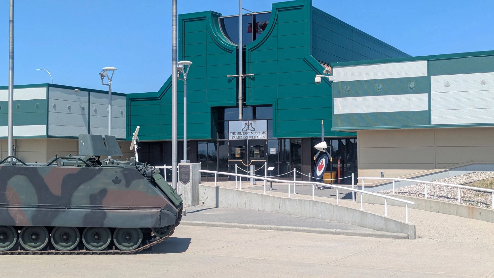Exterior of The Military Museum with glass entrance and armored vehicle on display.
