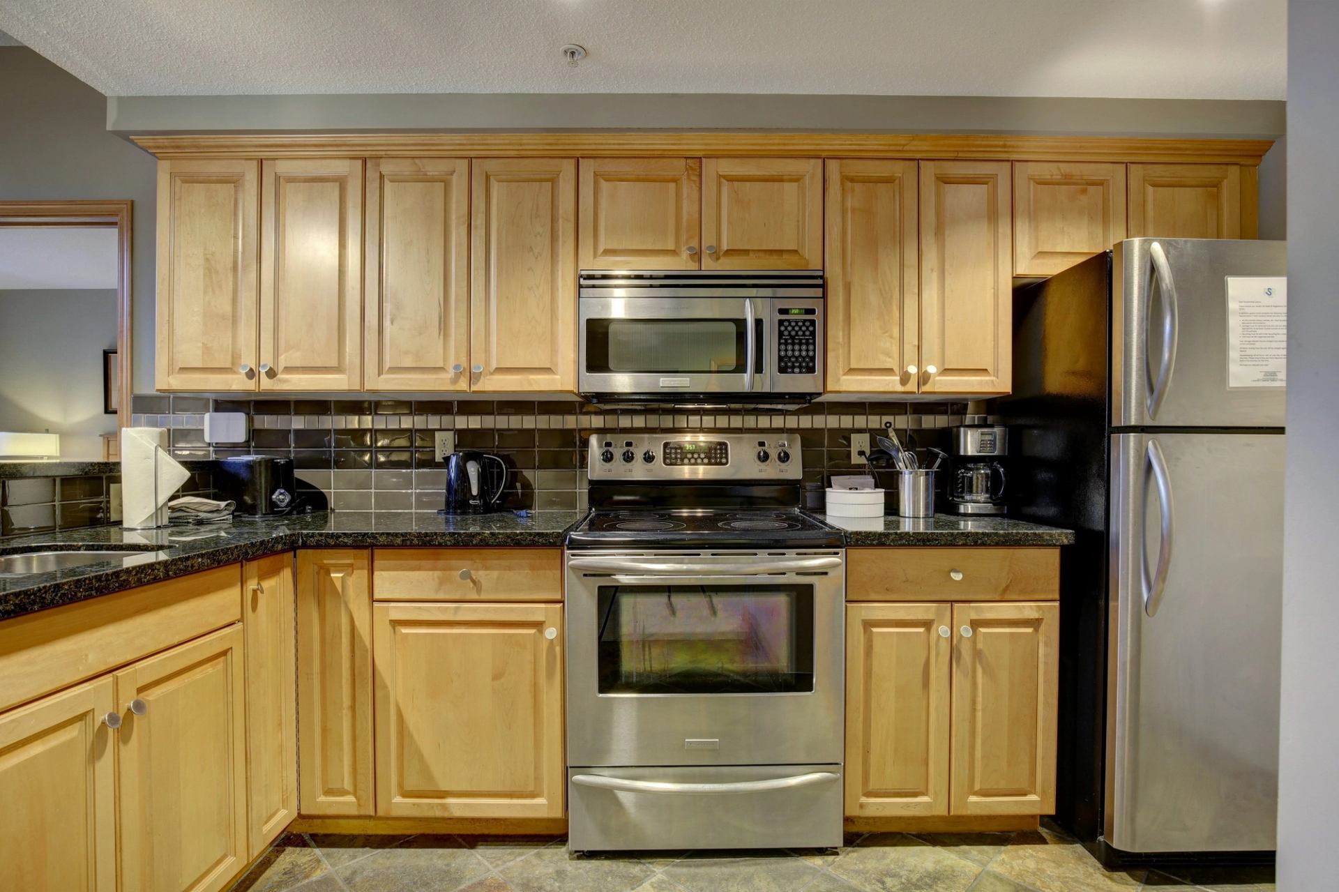 Kitchen with wood cabinets, stainless appliances, and dark countertops.