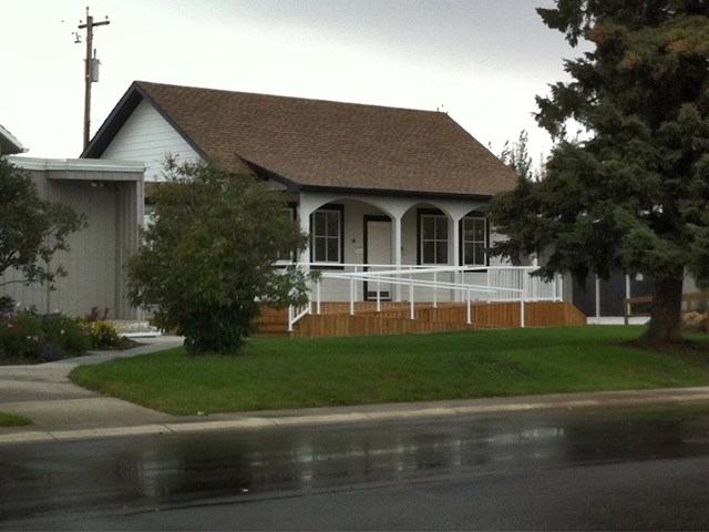 White house with porch and wet street at Carstairs Visitor Centre.